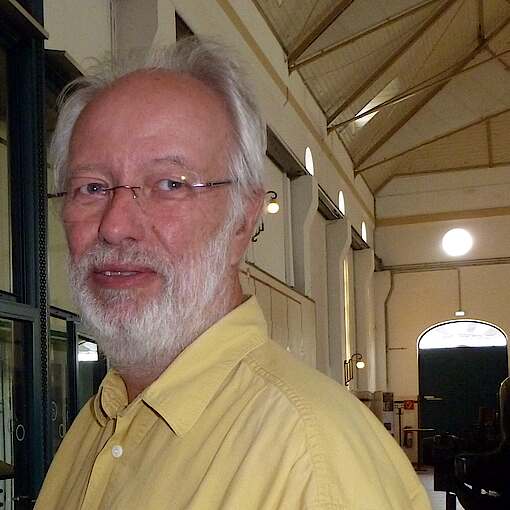 Portrait Dieter Hasloop seitlich in die Kamera schauend in der großen Halle