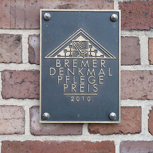 Plakette mit Aufschrift an Backsteinmauer angebracht