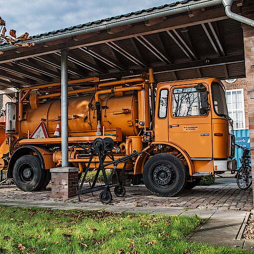Oldtimer-Lastwagen in Orange steht unter Überdachung